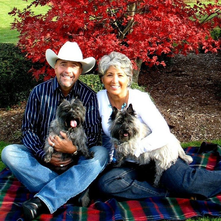 A man and woman sitting on the ground with two dogs.